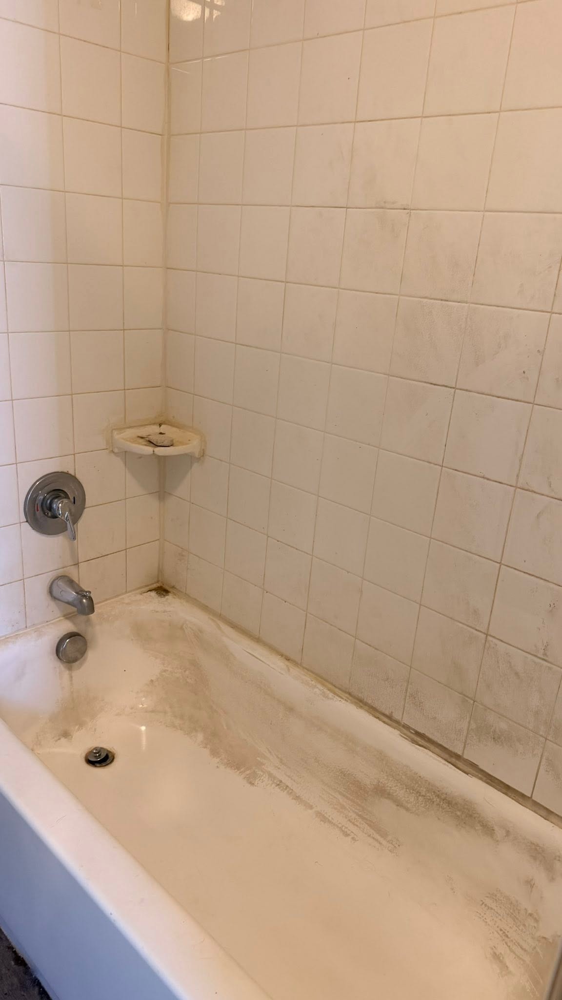 Grimy bathtub with stained tiles before cleaning